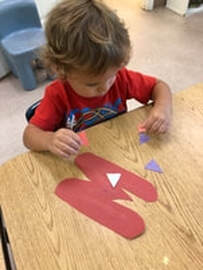 Student makes a paper collage at his day care, Fort Myers FL