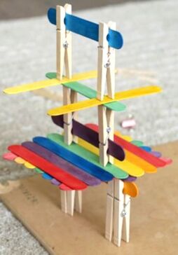Student construction of a tower made of popsicle sticks and clothes line clips during Pre-K STEAM