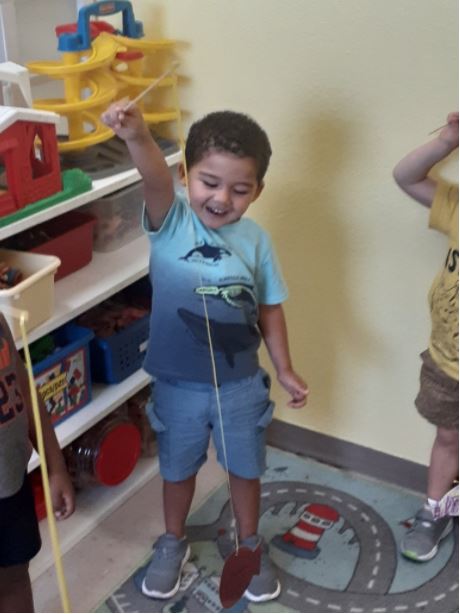 Student plays with pretend fishing poll at his preschool in Lehigh Acres FL